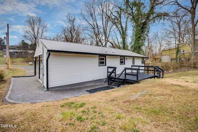 exterior space featuring a deck, a lawn, and metal roof