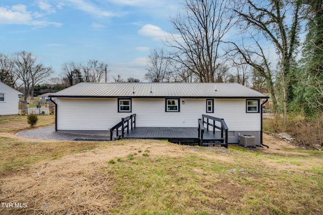 back of property featuring a wooden deck, central AC unit, metal roof, and a yard