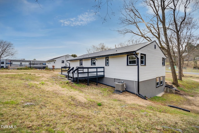 back of house with metal roof, a wooden deck, cooling unit, and a lawn