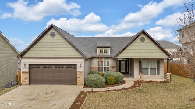 craftsman-style house featuring concrete driveway, stone siding, an attached garage, fence, and a front lawn