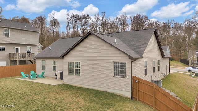 rear view of house with a patio, a shingled roof, a lawn, central AC, and fence