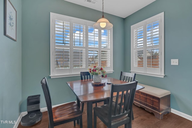 dining space with dark wood-style floors, visible vents, and baseboards