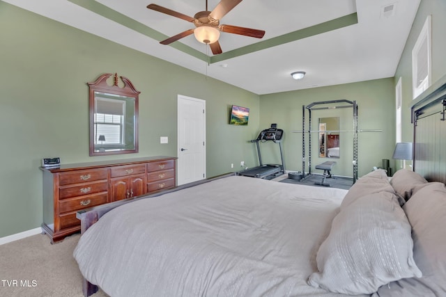 bedroom with baseboards, visible vents, a raised ceiling, a ceiling fan, and light colored carpet