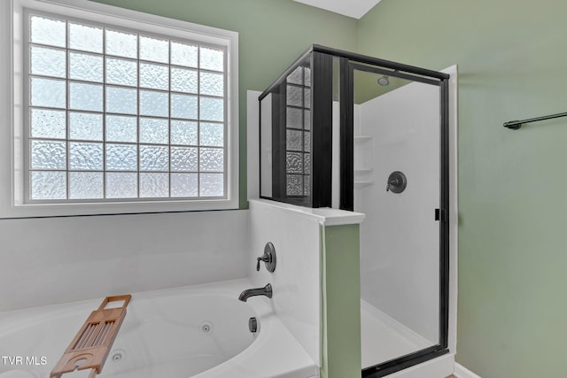 bathroom featuring a tub with jets, a stall shower, and a healthy amount of sunlight