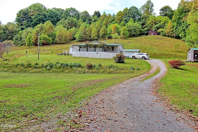 view of front of property with an outbuilding, driveway, a storage shed, and a front yard