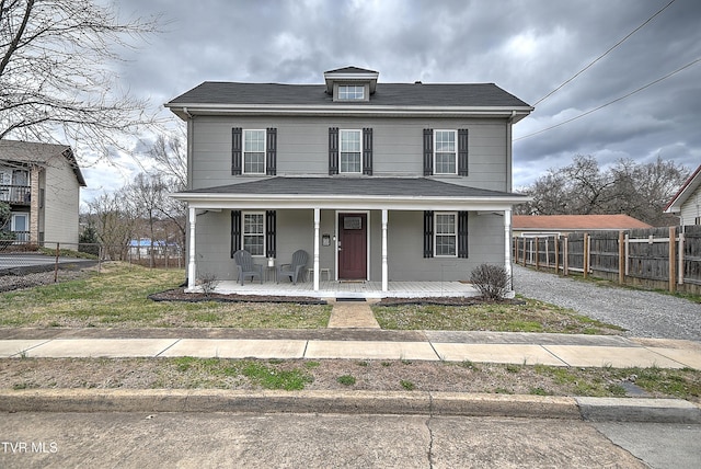 american foursquare style home with covered porch, driveway, and fence