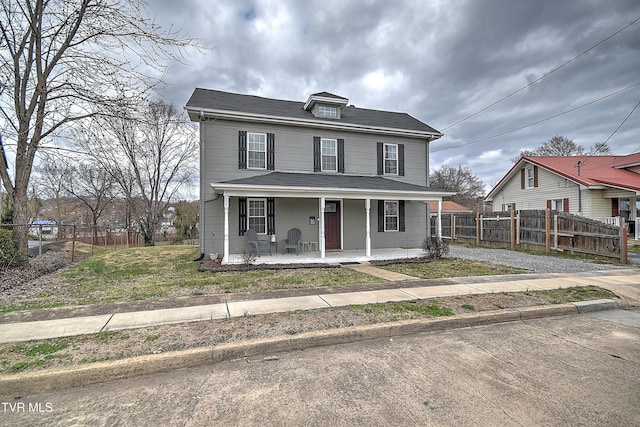 view of front of home with driveway, fence, and a porch