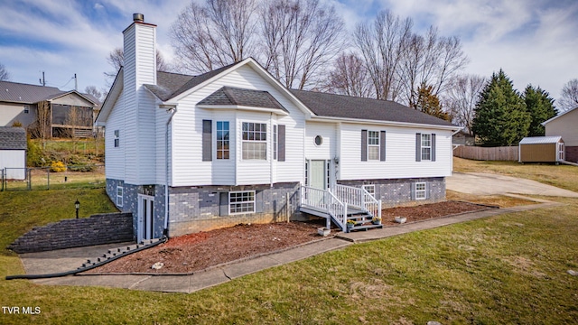 split foyer home with a front lawn, fence, and a chimney