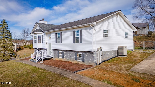 exterior space with a yard, a chimney, central AC, and fence