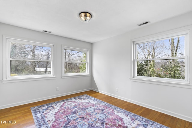 empty room featuring visible vents, baseboards, and wood finished floors