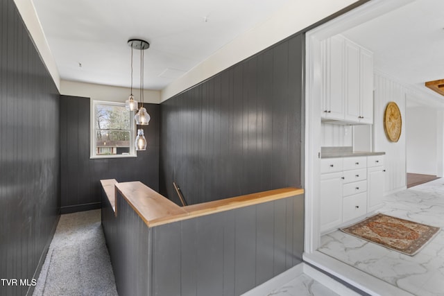 interior space with marble finish floor, hanging light fixtures, light countertops, and white cabinetry