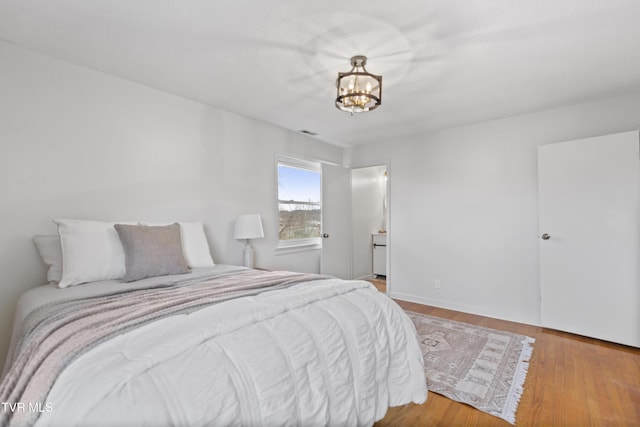 bedroom with wood finished floors, visible vents, and an inviting chandelier