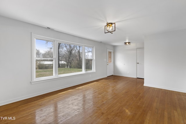 unfurnished room with hardwood / wood-style flooring, baseboards, and visible vents