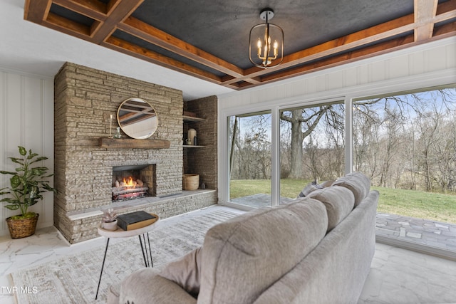 living room with marble finish floor, an inviting chandelier, a tray ceiling, a fireplace, and a decorative wall