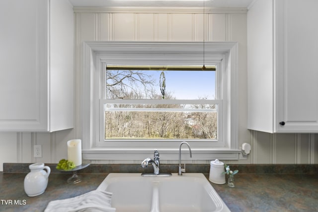 interior details featuring dark countertops, a sink, and white cabinets