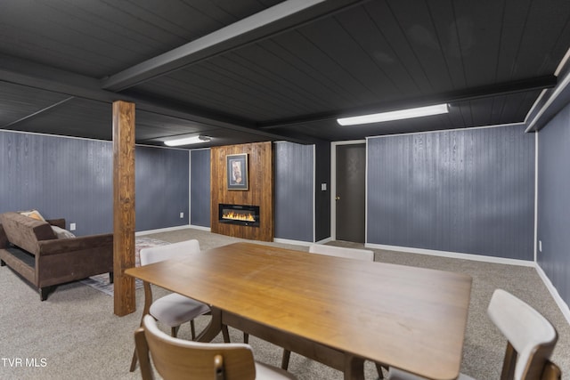 interior space featuring wooden walls, baseboards, a glass covered fireplace, carpet flooring, and beam ceiling