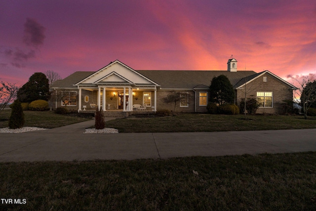 greek revival house with a porch, concrete driveway, and a yard