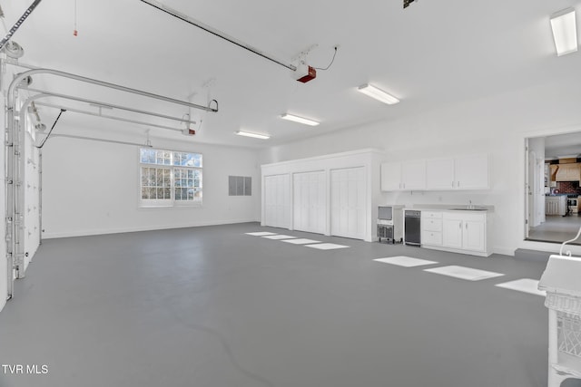 garage featuring a garage door opener, a sink, and baseboards