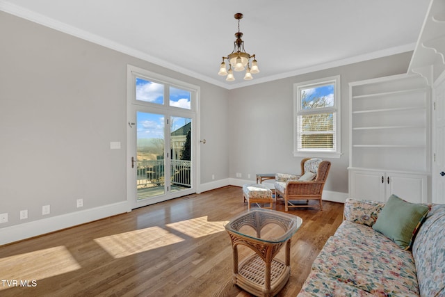 living area featuring baseboards, an inviting chandelier, wood finished floors, and crown molding