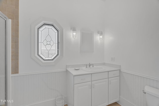 full bath with toilet, a shower, wainscoting, and vanity