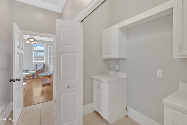 laundry area featuring crown molding, baseboards, and light tile patterned floors