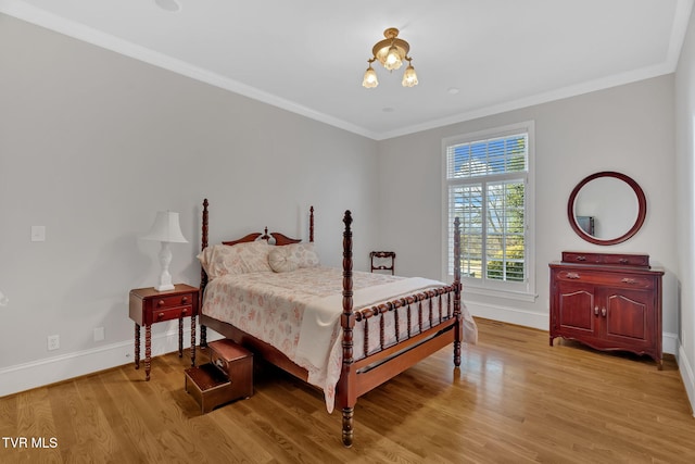 bedroom featuring light wood-type flooring, an inviting chandelier, baseboards, and crown molding