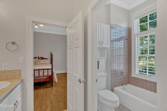 ensuite bathroom featuring ensuite bathroom, ornamental molding, wood finished floors, and a healthy amount of sunlight