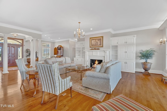 living room featuring light wood finished floors, decorative columns, baseboards, ornamental molding, and a fireplace