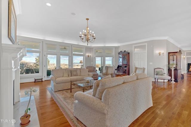 living room with light wood-type flooring, an inviting chandelier, a fireplace with flush hearth, and ornamental molding