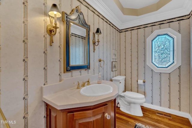 half bathroom featuring visible vents, ornamental molding, wood finished floors, and toilet