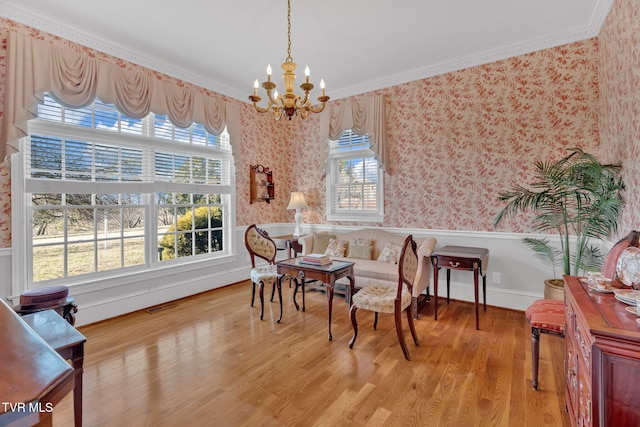 living area featuring wood finished floors, visible vents, wallpapered walls, an inviting chandelier, and crown molding