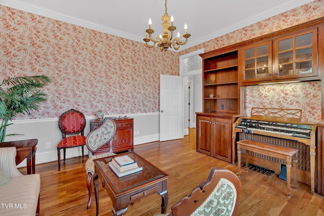 living room with a notable chandelier, light wood-style floors, ornamental molding, wainscoting, and wallpapered walls