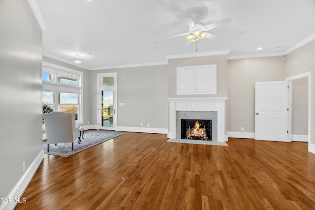 unfurnished living room with ornamental molding, baseboards, and wood finished floors