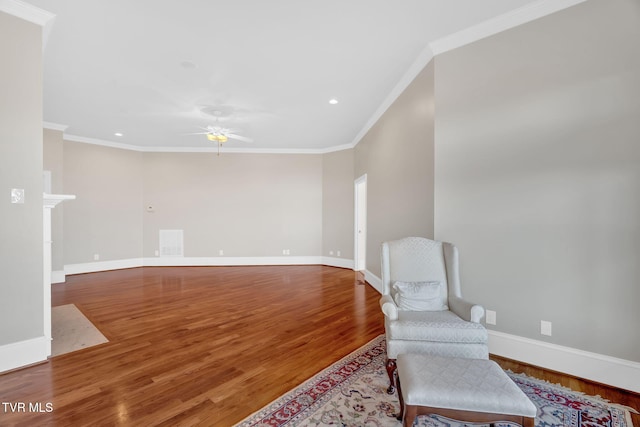 living area with visible vents, baseboards, a ceiling fan, wood finished floors, and crown molding