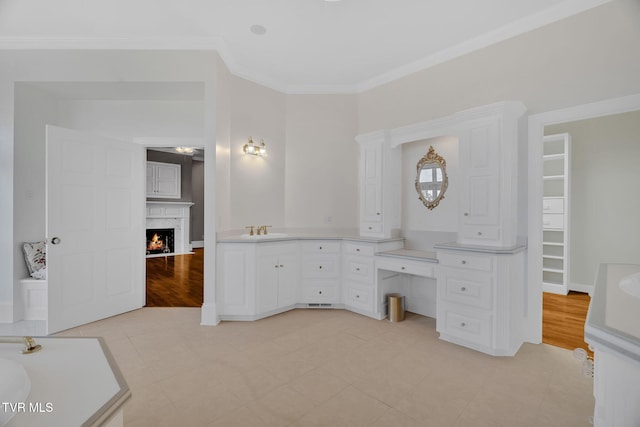 bathroom with crown molding, vanity, wood finished floors, a lit fireplace, and baseboards