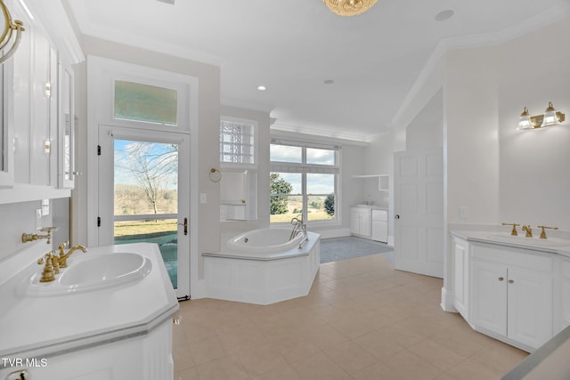 full bath featuring a bath, crown molding, two vanities, and a sink