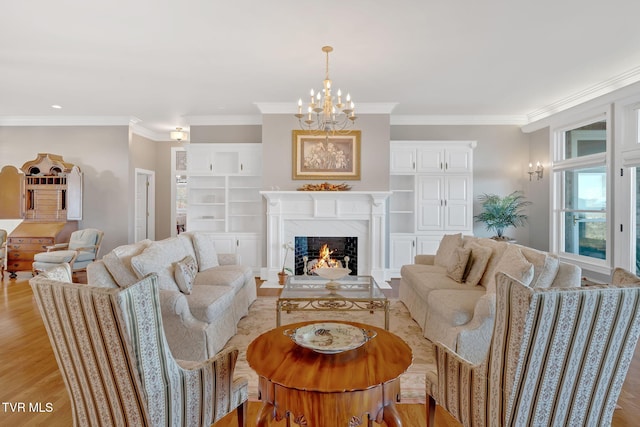 living area with built in shelves, a fireplace, an inviting chandelier, light wood-style floors, and ornamental molding