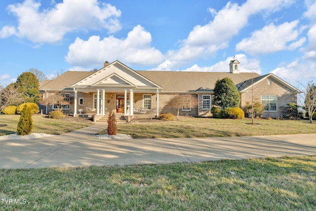 greek revival inspired property featuring a front yard, brick siding, and a chimney