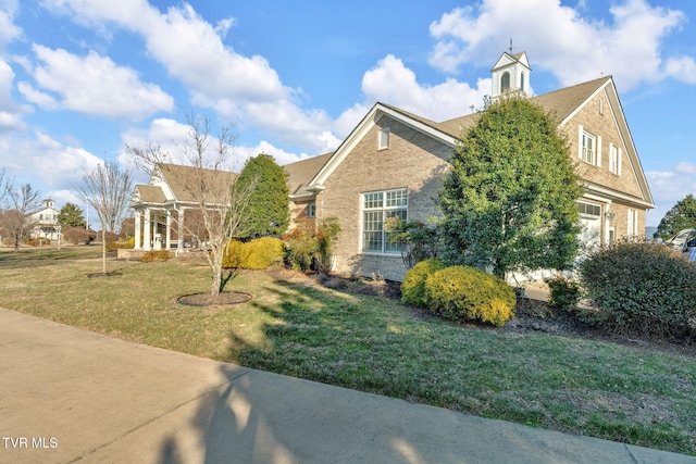 view of front facade with a garage, brick siding, and a front yard