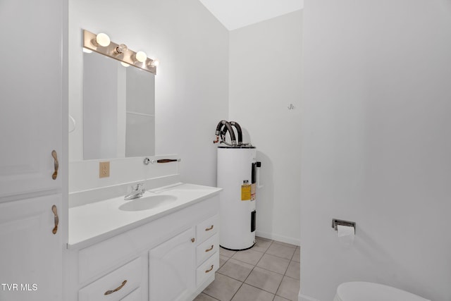 bathroom featuring toilet, electric water heater, vanity, tile patterned flooring, and baseboards