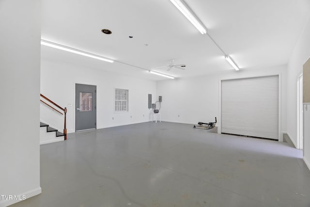 garage featuring electric panel, baseboards, and a ceiling fan