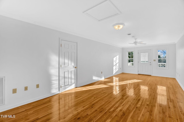 interior space with ornamental molding, light wood-type flooring, a ceiling fan, and baseboards