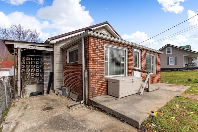 view of side of property featuring a yard, brick siding, and fence