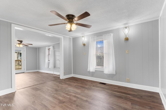 spare room featuring ornamental molding, visible vents, a textured ceiling, and wood finished floors