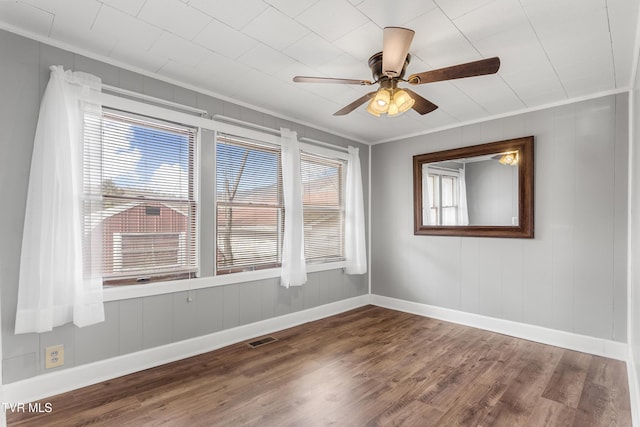 spare room featuring crown molding, visible vents, ceiling fan, wood finished floors, and baseboards