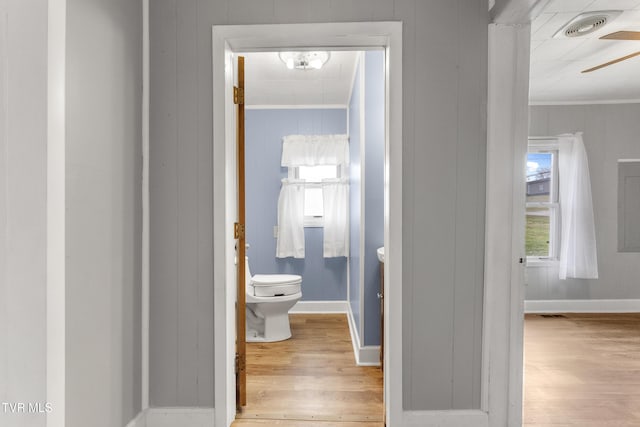 hall with baseboards, wood finished floors, and crown molding