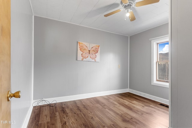 empty room with baseboards, wood finished floors, visible vents, and a ceiling fan