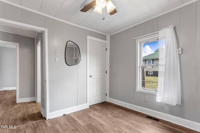 unfurnished bedroom featuring ornamental molding, visible vents, baseboards, and wood finished floors