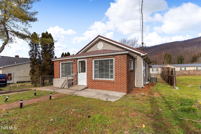 bungalow-style house featuring brick siding, fence, a front lawn, and central AC unit