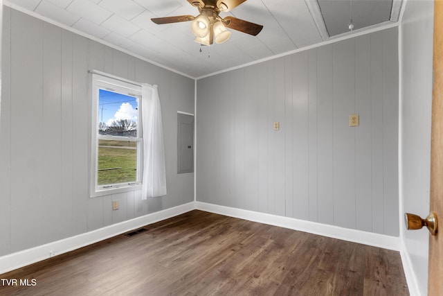 unfurnished room featuring visible vents, ornamental molding, electric panel, dark wood finished floors, and attic access